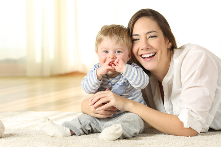 Smiley mother and baby looking at you at home